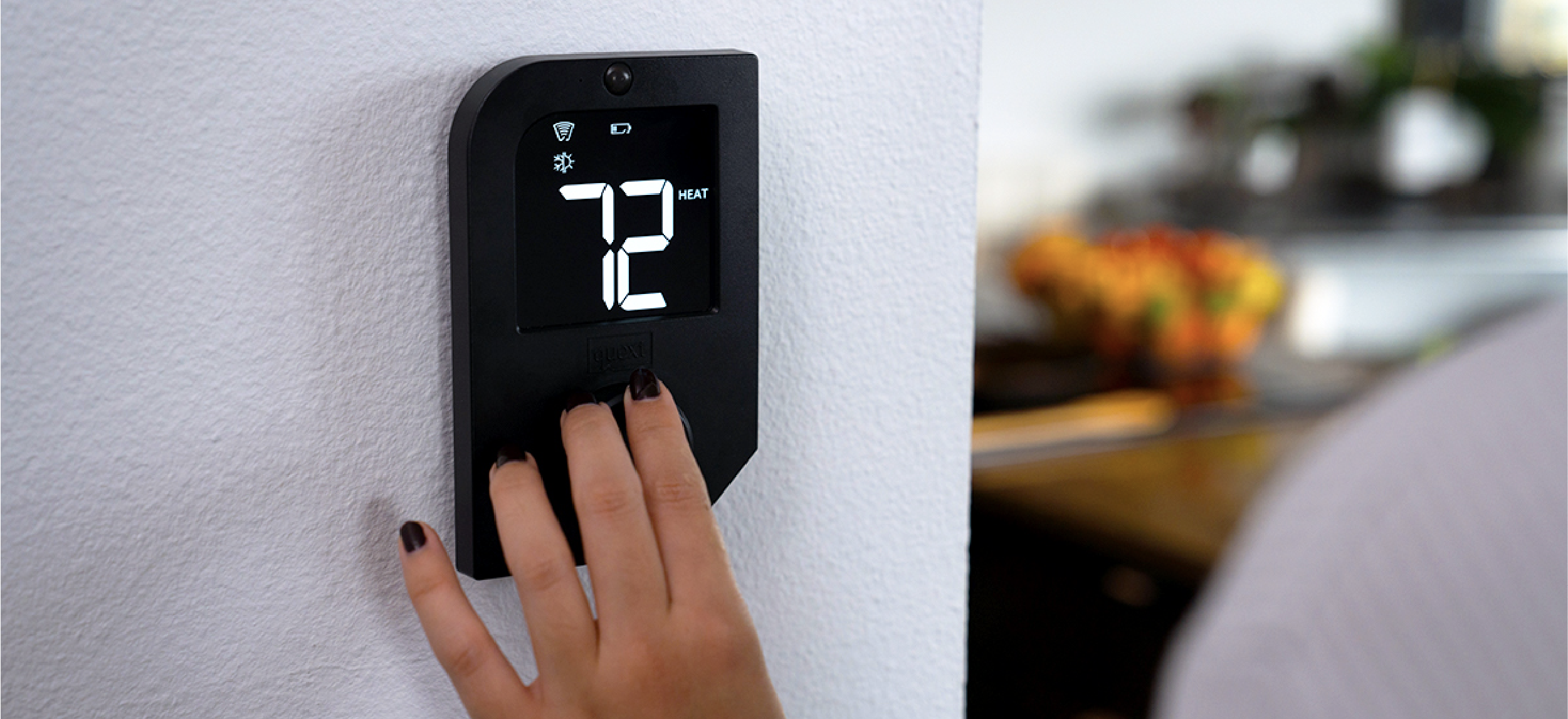 A multifamily resident using a Quext IoT smart thermostat.